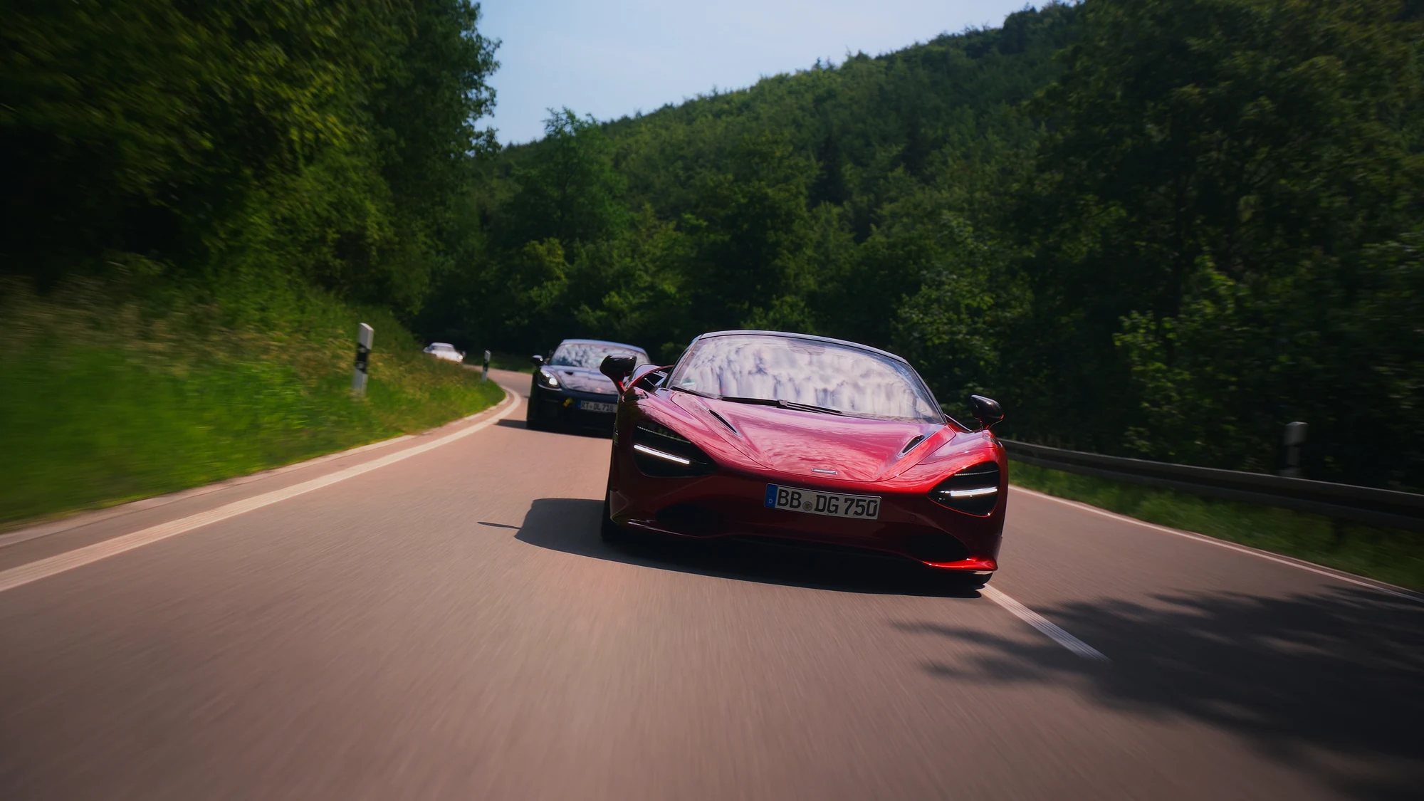 Roter McLaren und Porsche auf einer kurvigen Waldstraße
