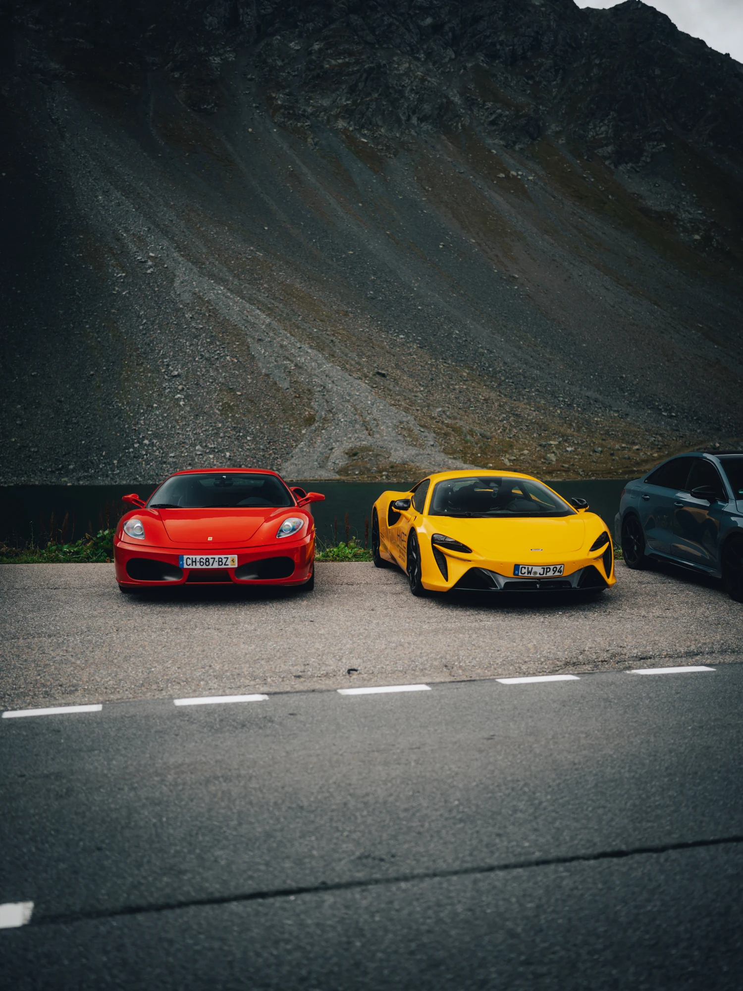 Roter und gelber Sportwagen beim gemeinsamen Stopp in den Schweizer Alpen