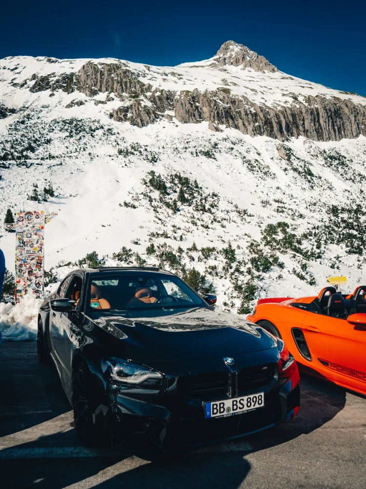 Sportwagen vor schneebedeckten Alpengipfeln
