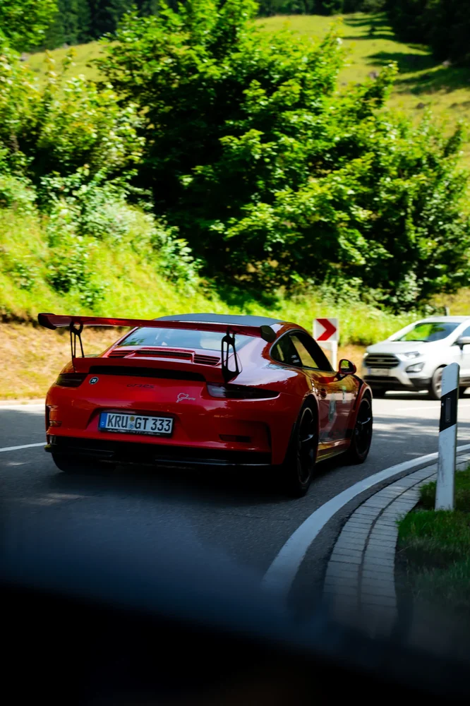 Roter Porsche auf einer kurvigen Alpenstraße