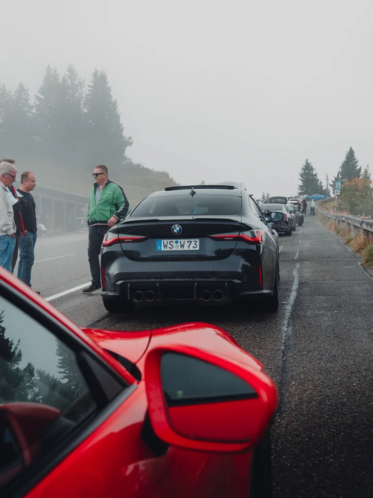 Blick vom roten Porsche auf die Sportwagenreihe im Herbstnebel