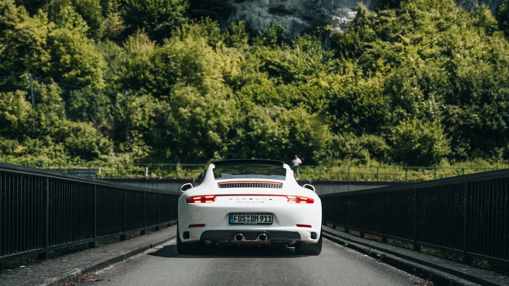 Weißer Porsche auf einer Straße vor der Felskulisse der Schwäbischen Alb