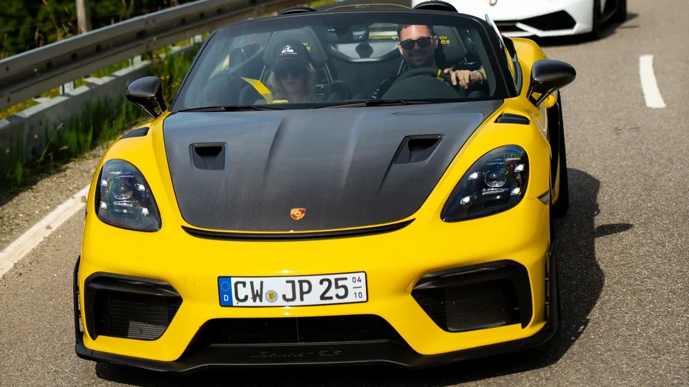 Gelber Porsche Spyder RS und Sportwagenkonvoi in den Alpen
