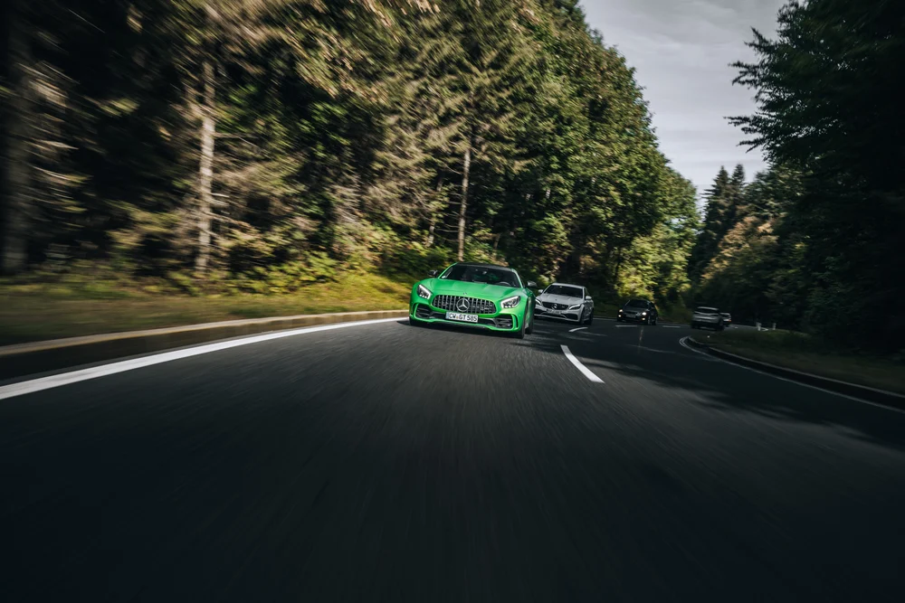 Grüner Mercedes-AMG auf der bewaldeten Alpenstraße