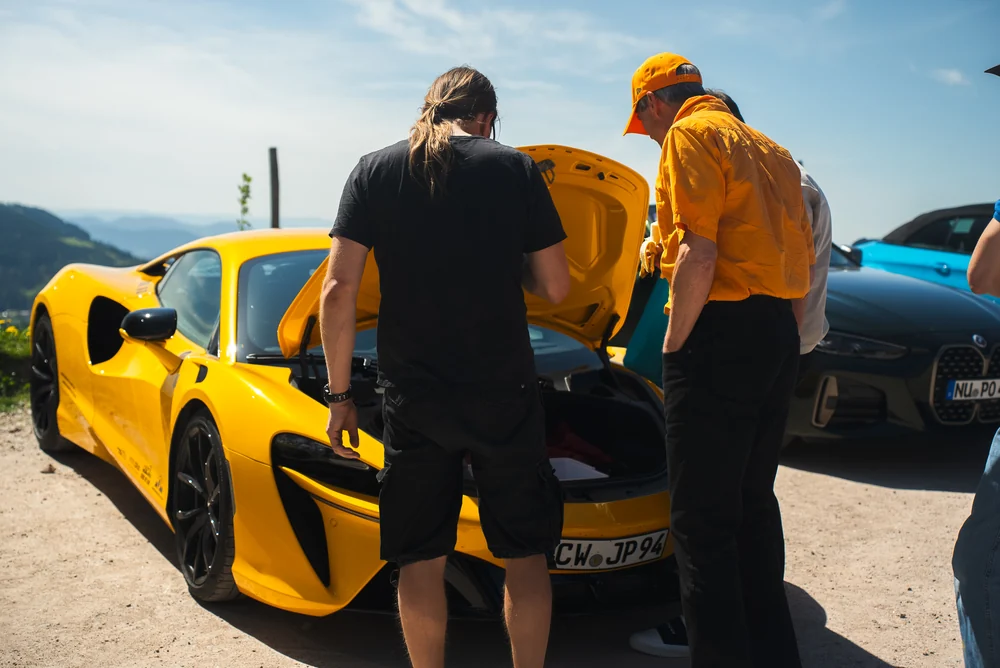 Teilnehmer im Gespräch am gelben McLaren