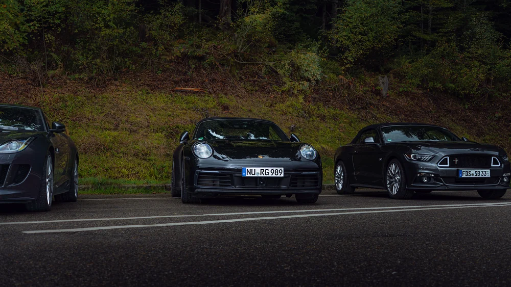 Porsche 911 und weitere Sportwagen vor dem Herbstwald