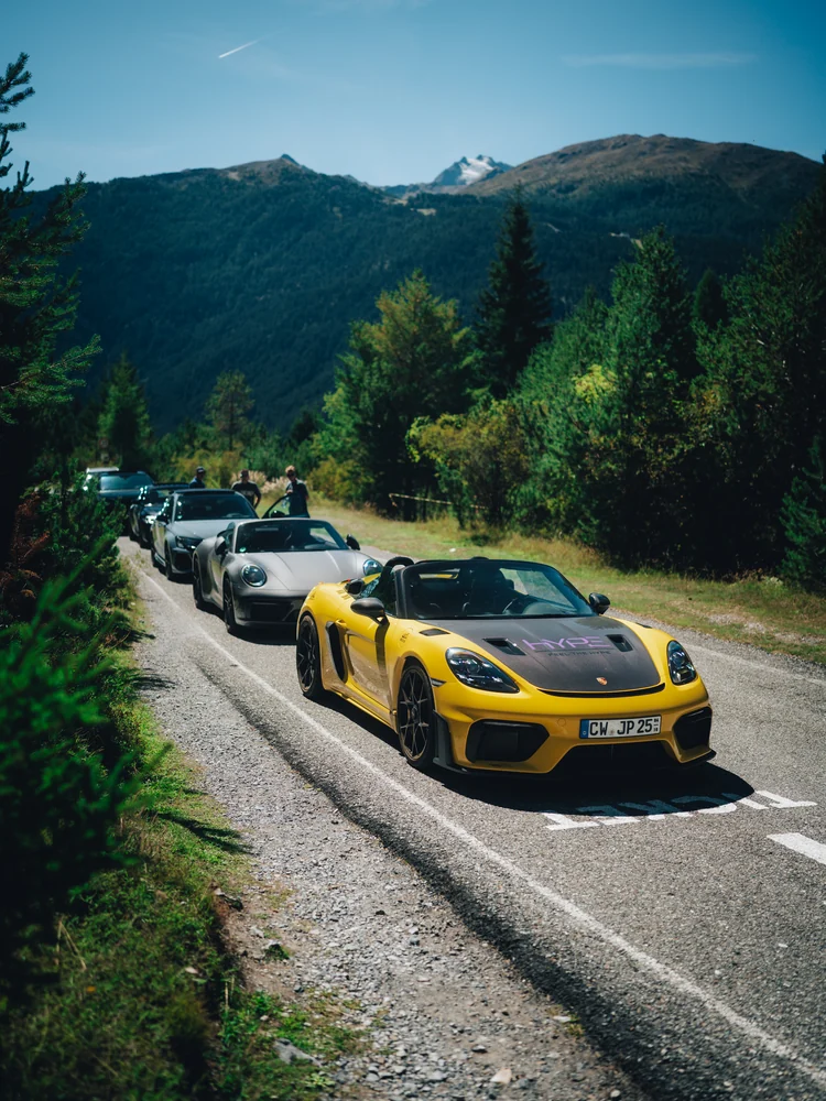 Gelber Porsche Spyder RS an der Spitze der Gruppe auf einer sonnigen Alpenstraße