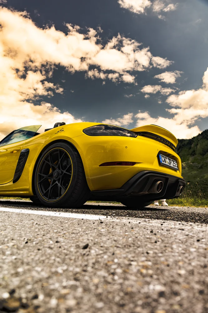 Gelber Porsche Spyder RS vor einem dramatischen Wolkenhimmel