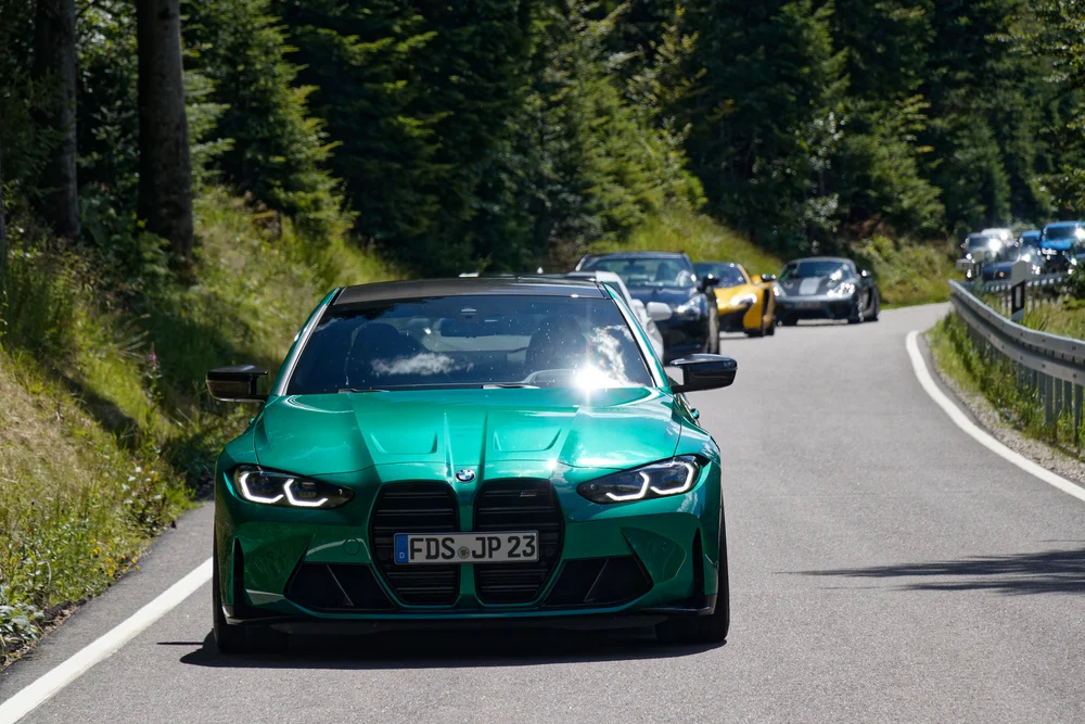 Grüner BMW führt die Fahrzeugkolonne durch den Schwarzwald
