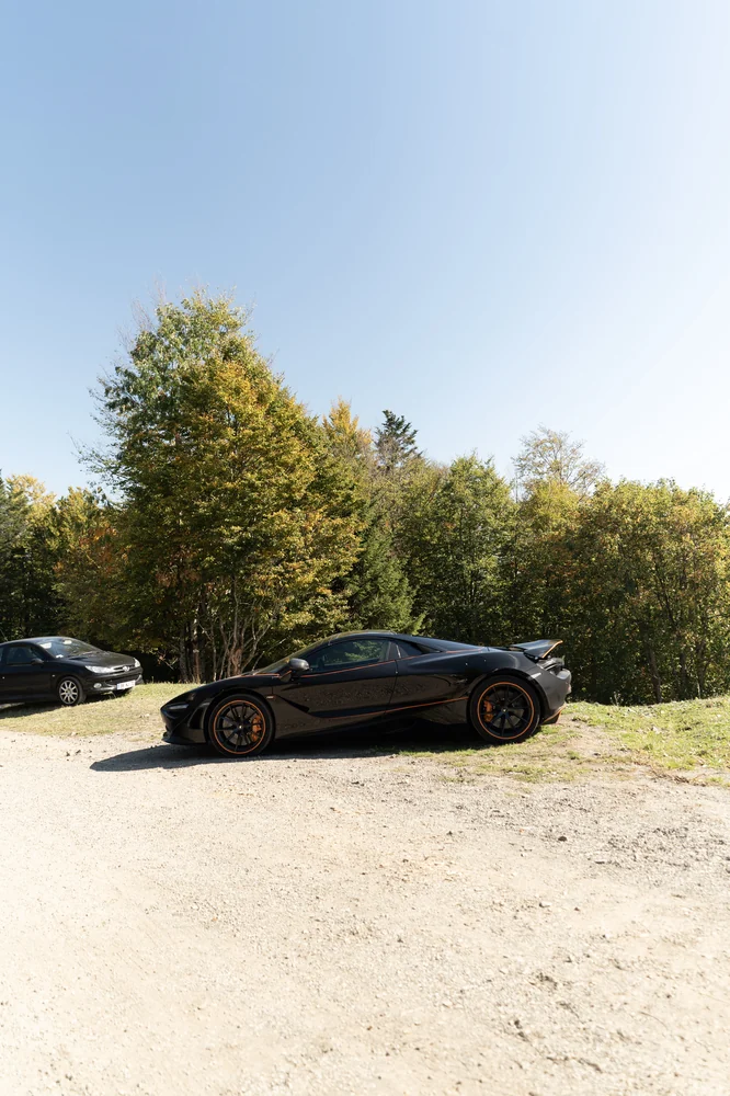 Schwarzer Porsche am sonnigen Waldparkplatz