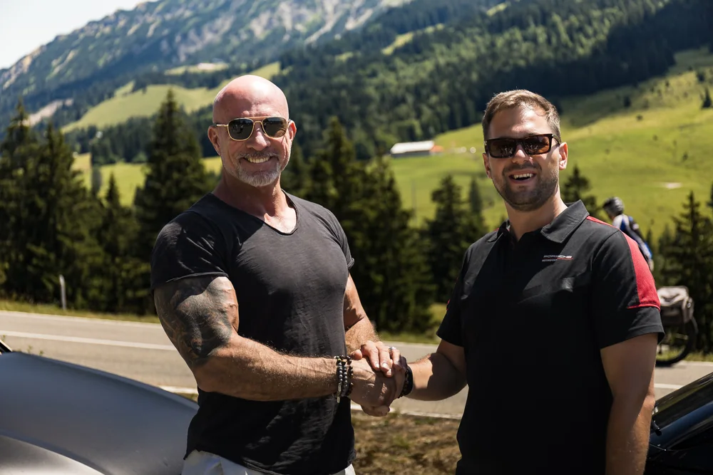 Zwei Teilnehmer begrüßen sich vor der Bergkulisse